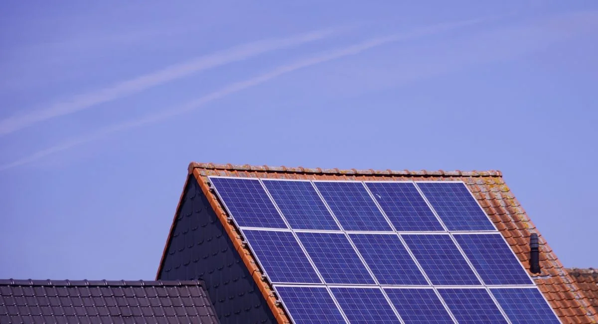 Close-up of solar panels on a tiled rooftop under a clear sky, showcasing renewable energy.