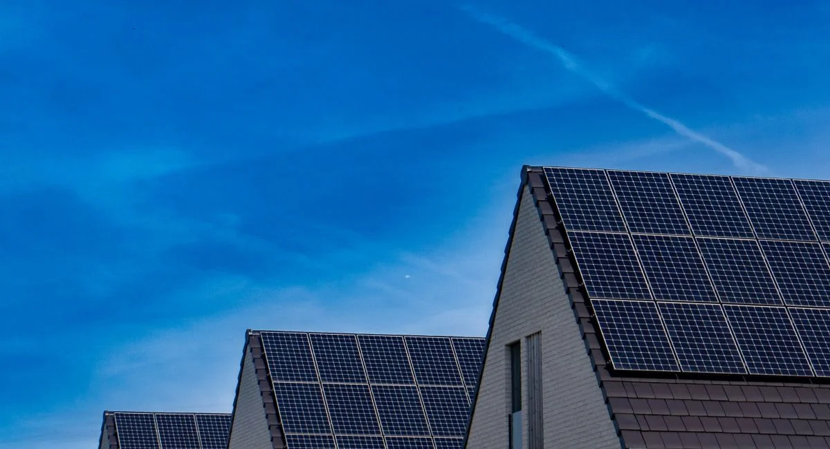 Contemporary homes featuring solar panels under a bright blue sky promoting renewable energy.