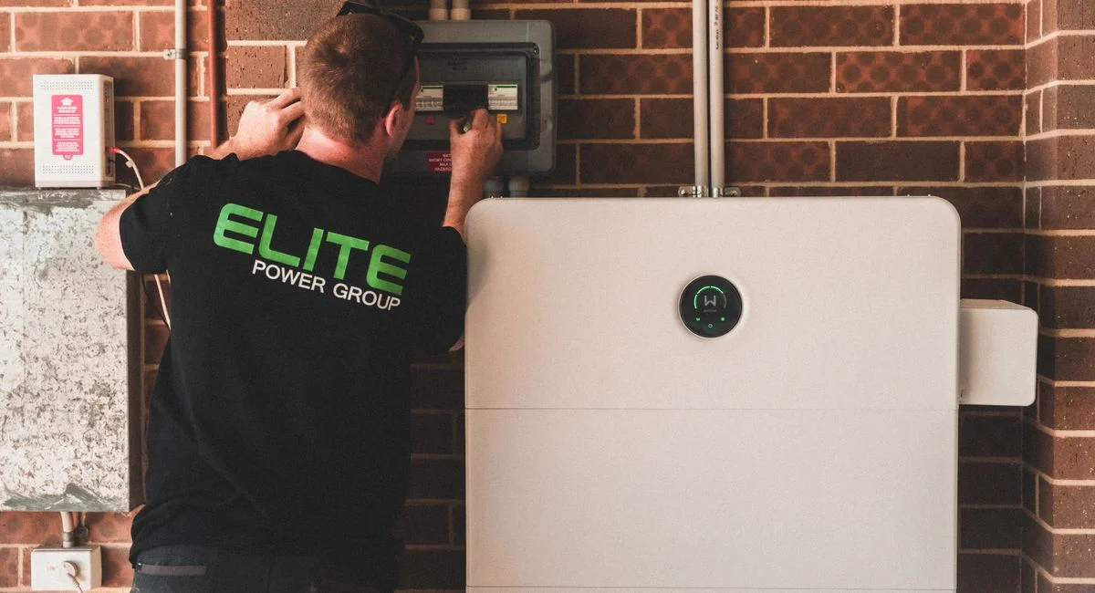 Electrician installing a home energy battery storage unit. Renewable and sustainable energy solution for residential use.