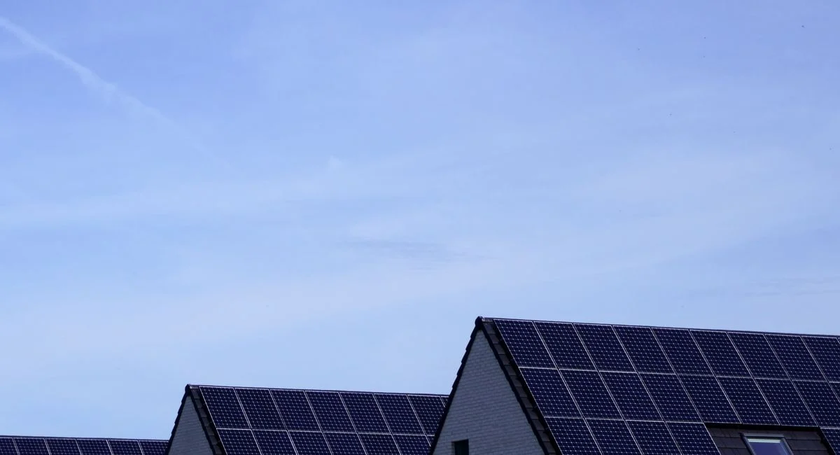 Modern Belgian houses with solar panels on rooftops under a clear blue sky.