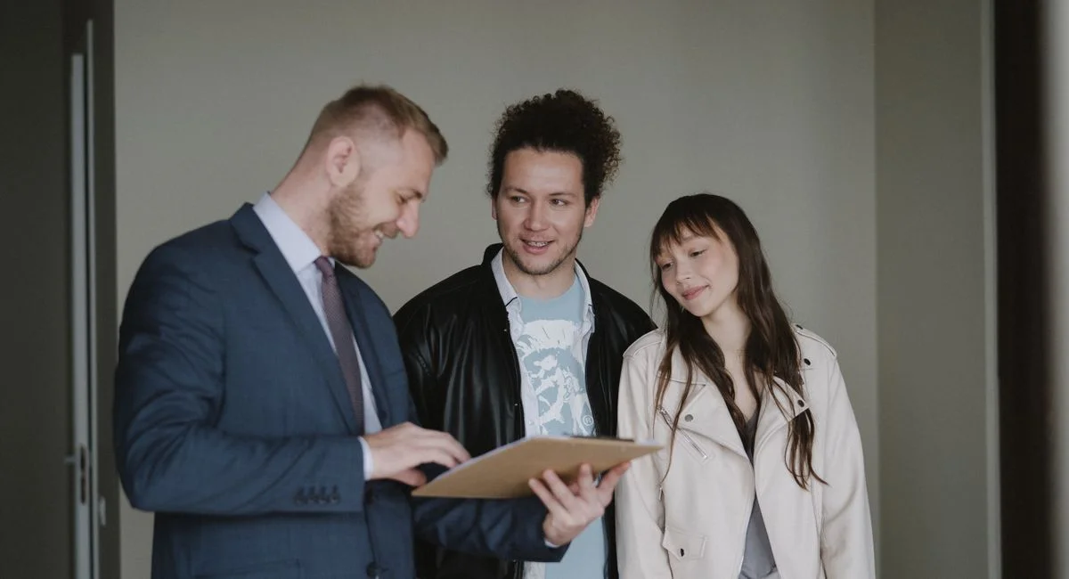 Happy couple meeting with a real estate agent discussing paperwork indoors.