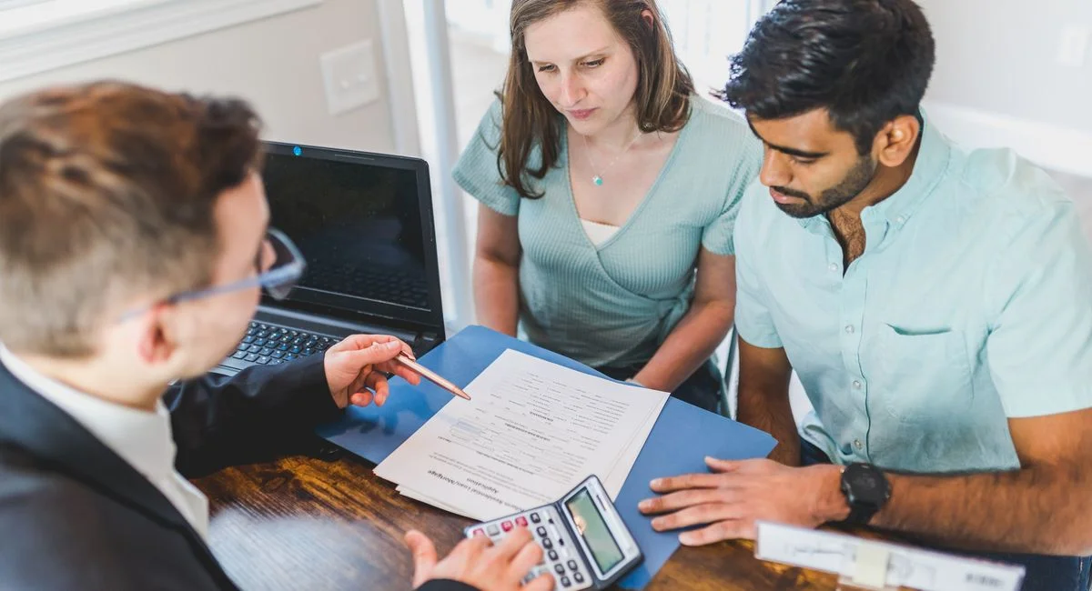 Young couple meeting with real estate agent to discuss property purchase.