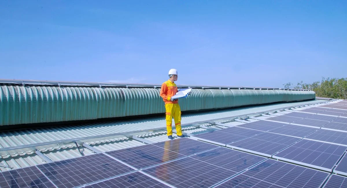 Technician examining solar panels on a rooftop, emphasizing renewable energy.