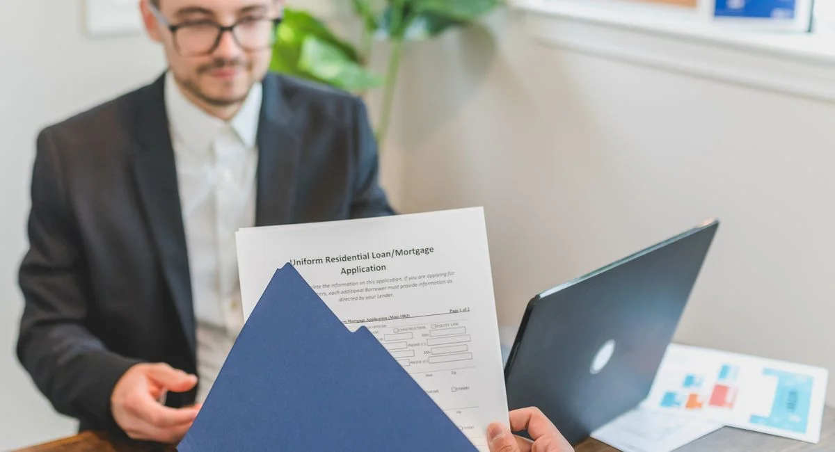 Mortgage broker and client discussing loan application with documents on table.