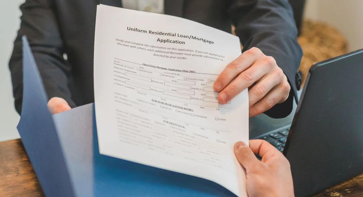 Professional setting showing hands exchanging a mortgage application document indoors.